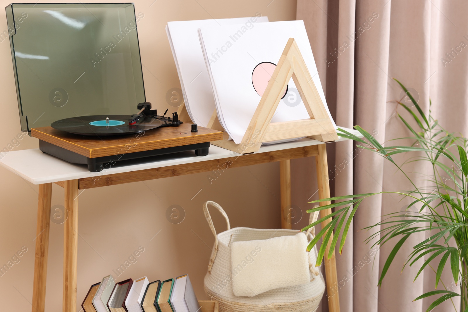 Photo of Stylish turntable with vinyl record on console table in cozy room