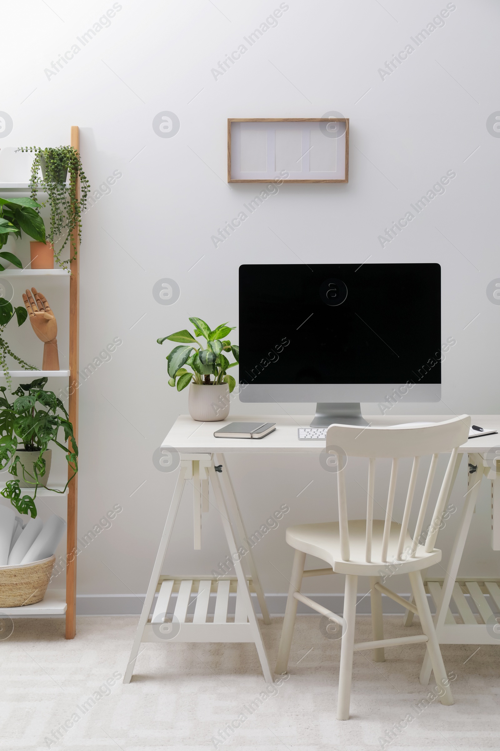 Photo of Spacious workspace with desk, chair, computer and potted plants at home