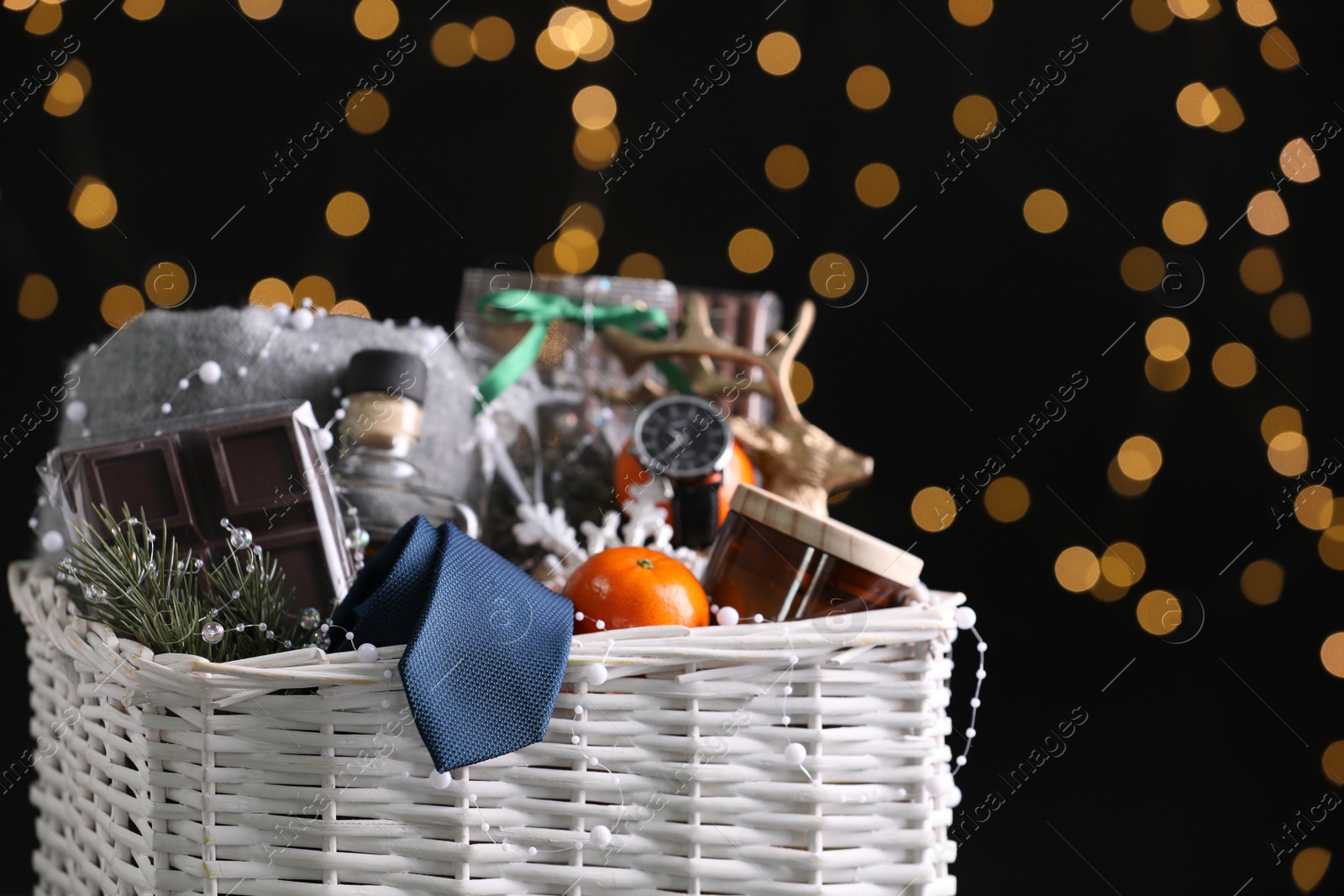 Photo of Wicker basket with Christmas gift set on black background against festive lights