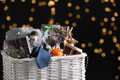 Wicker basket with Christmas gift set on black background against festive lights