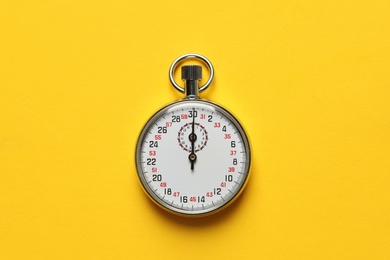 Vintage stopwatch on yellow background, top view