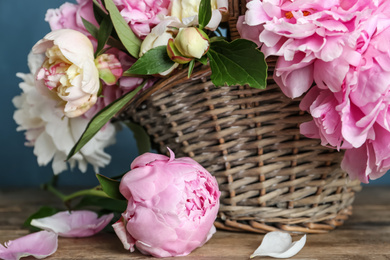 Beautiful peonies in wicker basket on wooden table