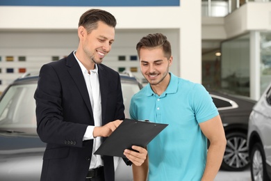Salesman consulting young man in car salon