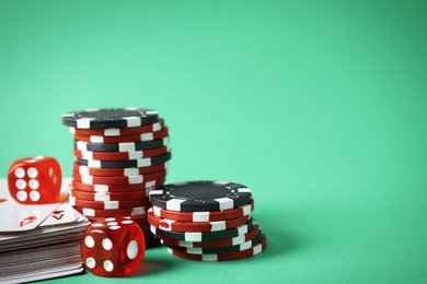 Photo of Poker chips, cards and dices on green background, space for text