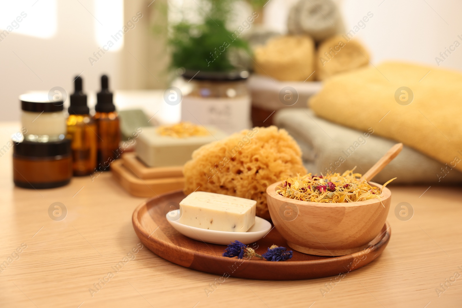 Photo of Dry flowers, loofah and soap bar on wooden table indoors. Spa time