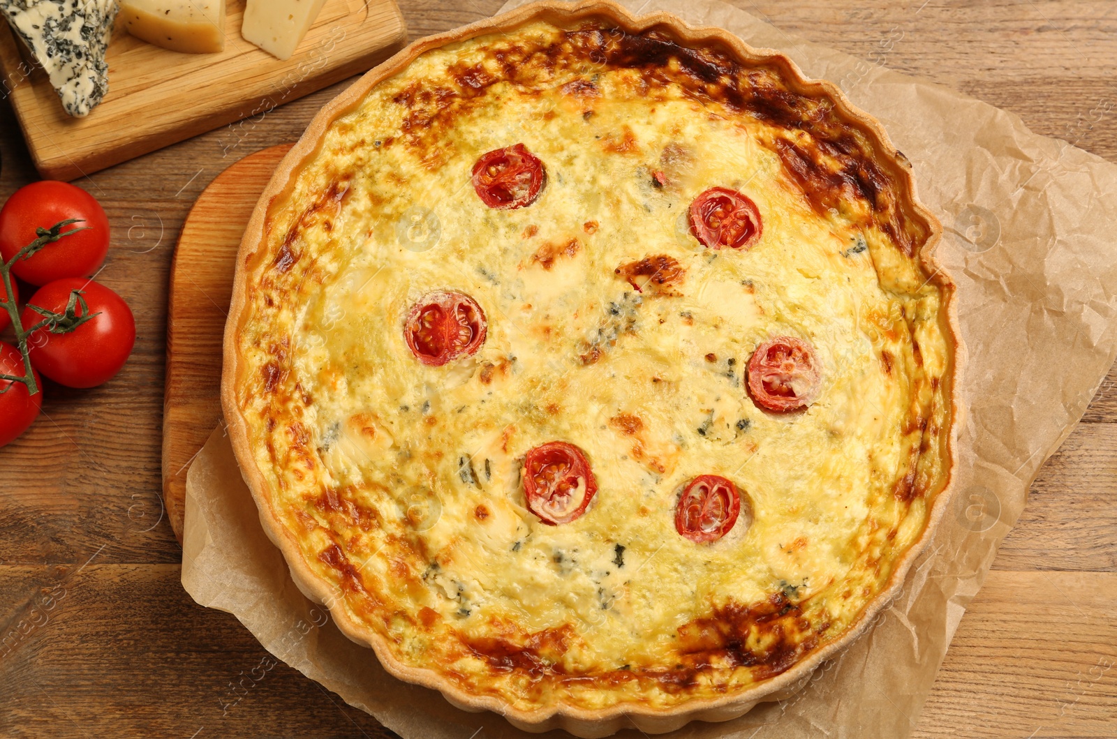 Photo of Delicious quiche with cheese and tomatoes on wooden table, top view