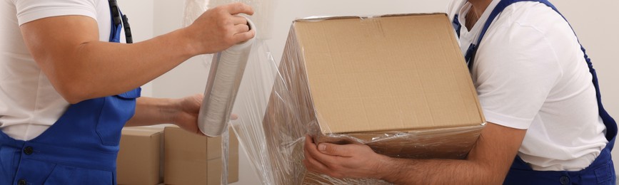 Image of Workers wrapping box in stretch film indoors, closeup. Banner design