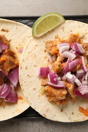 Photo of Delicious tacos with vegetables, meat and lime on grey textured table, top view