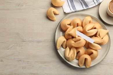 Tasty fortune cookies and paper with prediction on wooden table, flat lay. Space for text