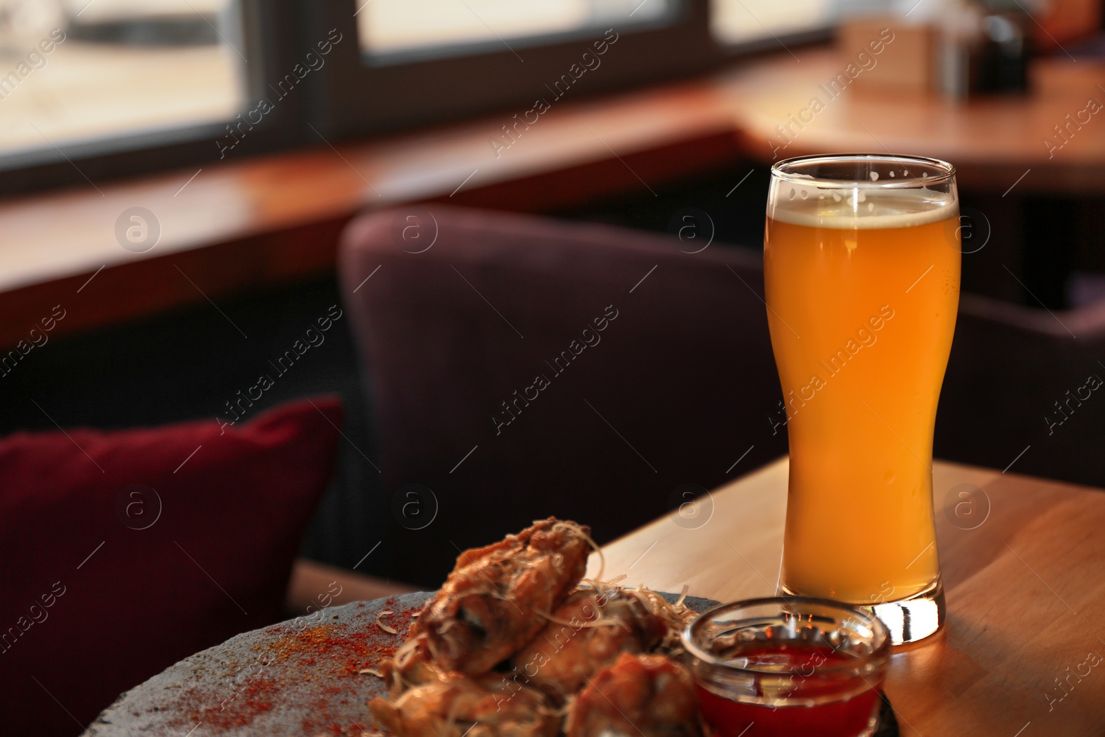 Photo of Fresh beer and tasty BBQ wings served on wooden table