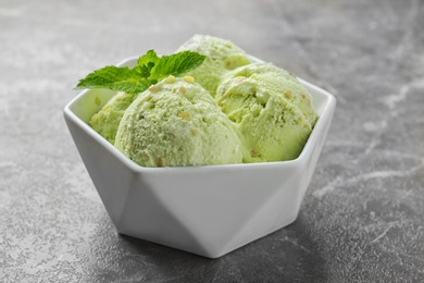 Photo of Delicious pistachio ice cream in bowl on grey marble table