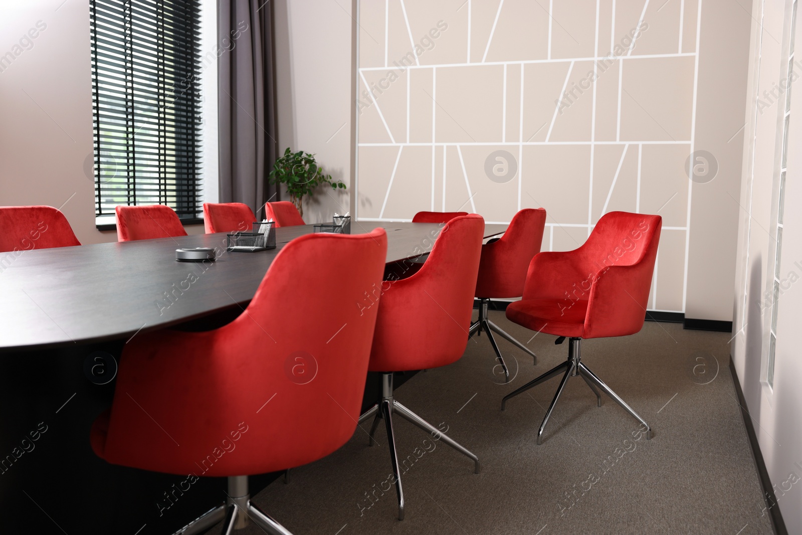 Photo of Stylish red office chairs and large wooden table in empty conference room