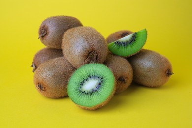 Photo of Heap of whole and cut fresh kiwis on yellow background