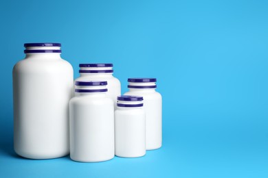 Photo of White medical bottles on light blue background, space for text