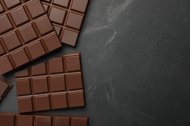 Pieces of tasty chocolate bars on grey table, flat lay. Space for text