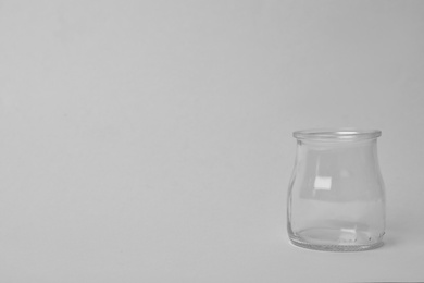 Photo of Open empty glass jar on light background, space for text