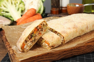 Delicious strudel with chicken and vegetables served on wooden table, closeup