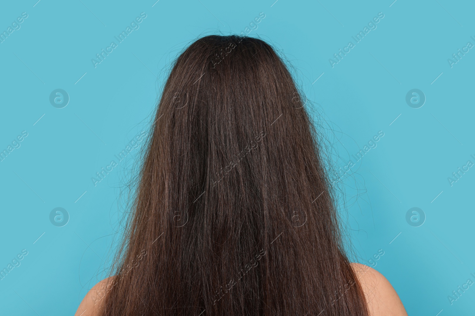 Photo of Woman with damaged hair before treatment on light blue background, back view