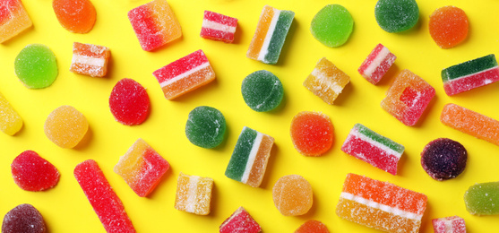 Image of Flat lay composition with delicious colorful candies on yellow background. Banner design 