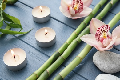 Photo of Bamboo branches, orchids and candles on wooden background