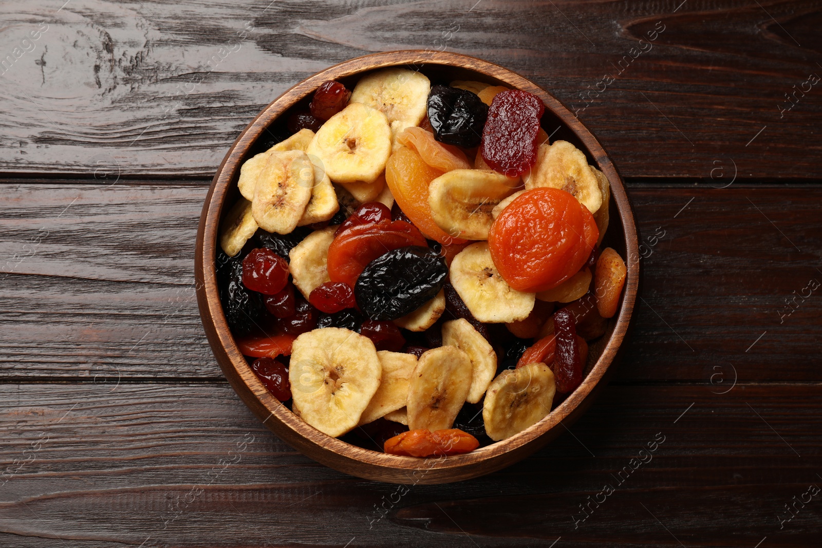 Photo of Mix of delicious dried fruits on wooden table, top view