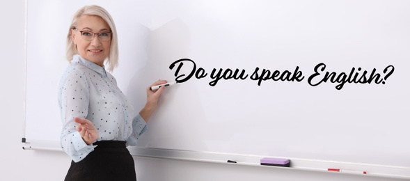 Image of Mature English teacher writing on whiteboard in classroom. Banner design