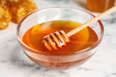 Photo of Tasty organic honey on marble table, closeup