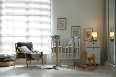 Photo of Baby room interior with crib, armchair and rocking horse. Idea for design
