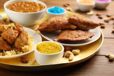 Traditional Indian food and color powder on wooden table, closeup. Holi festival celebration