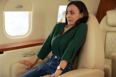 Nervous young woman suffering from aviophobia in airplane