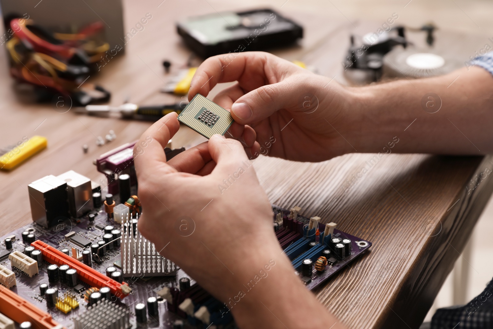 Photo of Male technician repairing motherboard at table, closeup