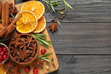 Photo of Flat lay composition with mulled wine ingredients on black wooden table. Space for text