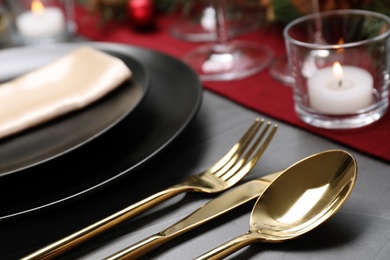 Photo of Christmas table setting with plates, cutlery, napkin and festive decor on grey background, closeup
