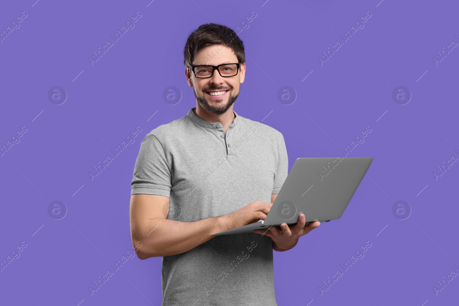 Photo of Happy man with laptop on lilac background