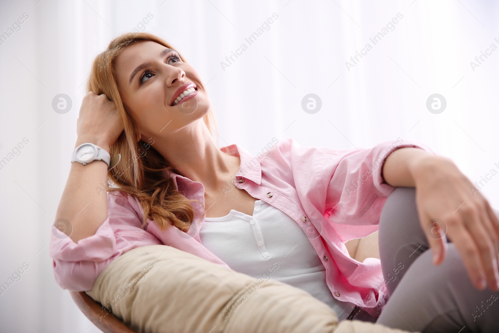 Photo of Young woman relaxing in papasan chair near window at home