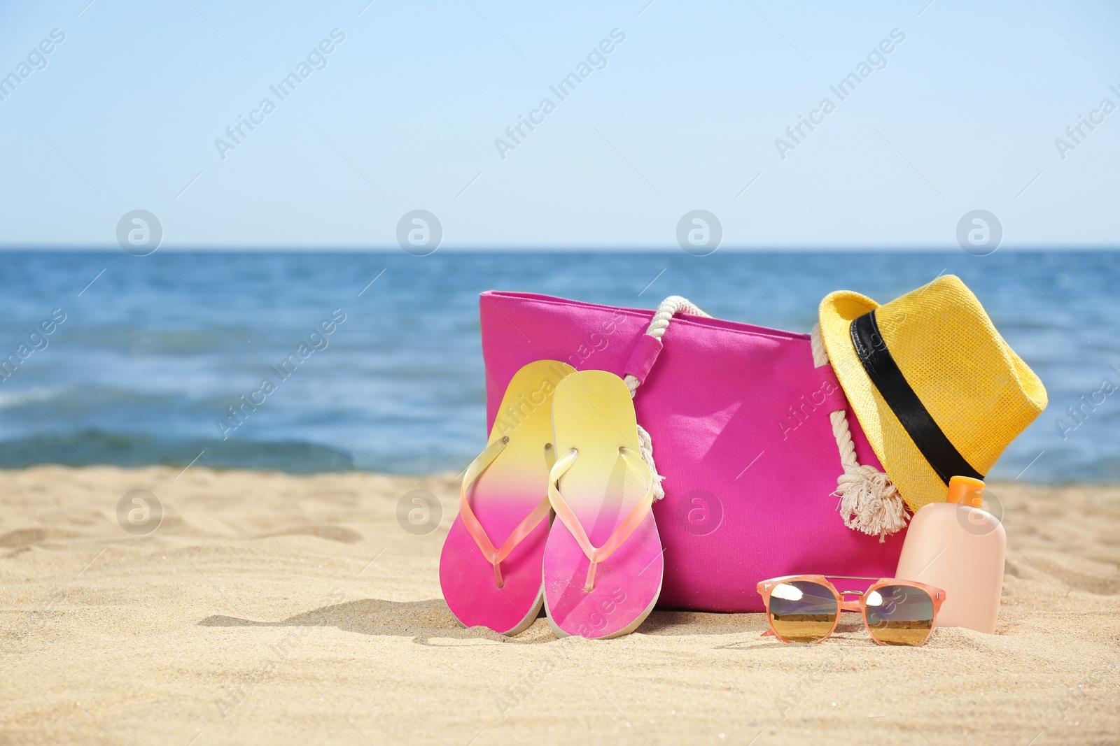 Photo of Stylish beach accessories on sand near sea. Space for text