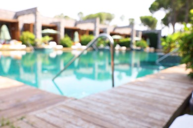 Outdoor swimming pool with wooden deck, blurred view. Luxury resort