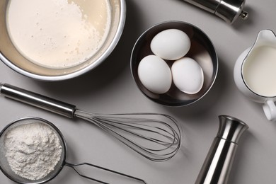 Photo of Flat lay composition with dough in bowl and metal whisk on grey background