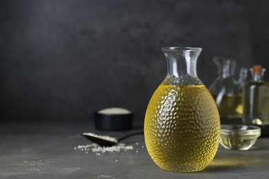 Photo of Fresh sesame oil in glass bottle on grey table. Space for text