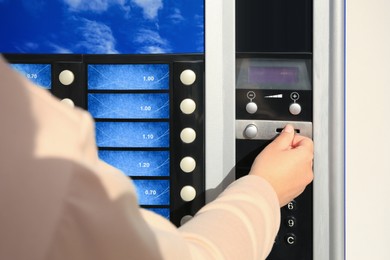 Using coffee vending machine. Woman inserting coin to pay for drink, closeup