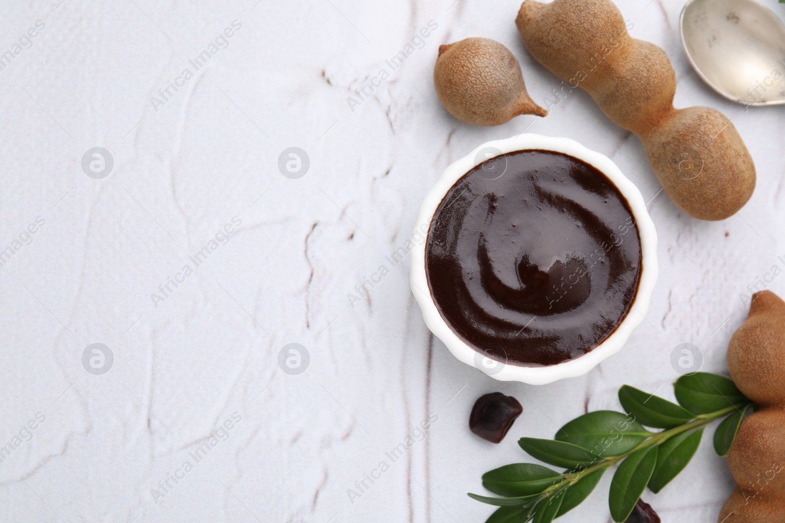 Bowl of tasty tamarind sauce and fresh pods on white textured table, flat lay. Space for text Photo of Bowl of tasty tamarind sauce and fresh pods on white textured table, flat lay. Space for text