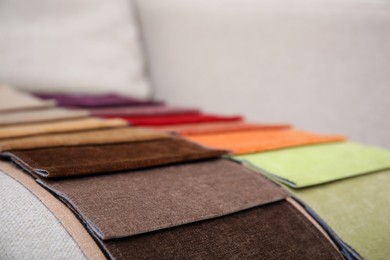 Photo of Catalog of colorful fabric samples on beige sofa, closeup