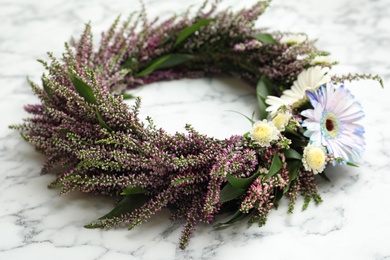 Photo of Beautiful autumnal wreath with heather flowers on white marble background, closeup