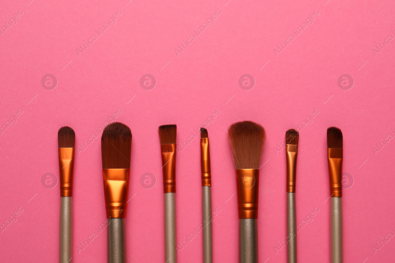 Photo of Set of makeup brushes on pink background, flat lay. Space for text