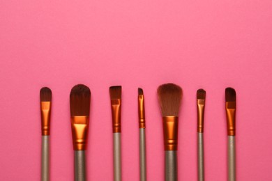 Set of makeup brushes on pink background, flat lay. Space for text