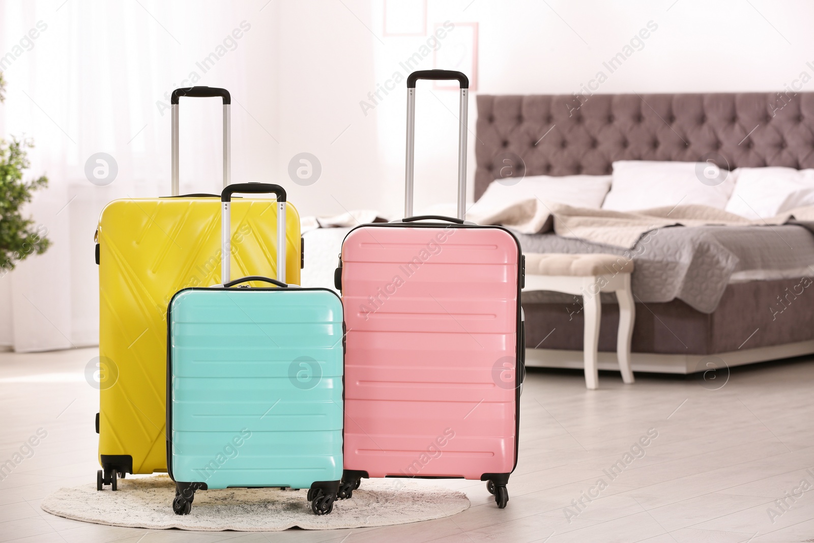 Photo of Colorful suitcases packed for journey in bedroom. Space for text