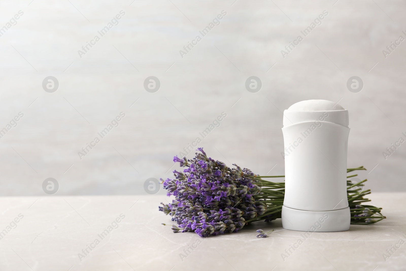 Photo of Female deodorant and lavender flowers on marble table. Space for text