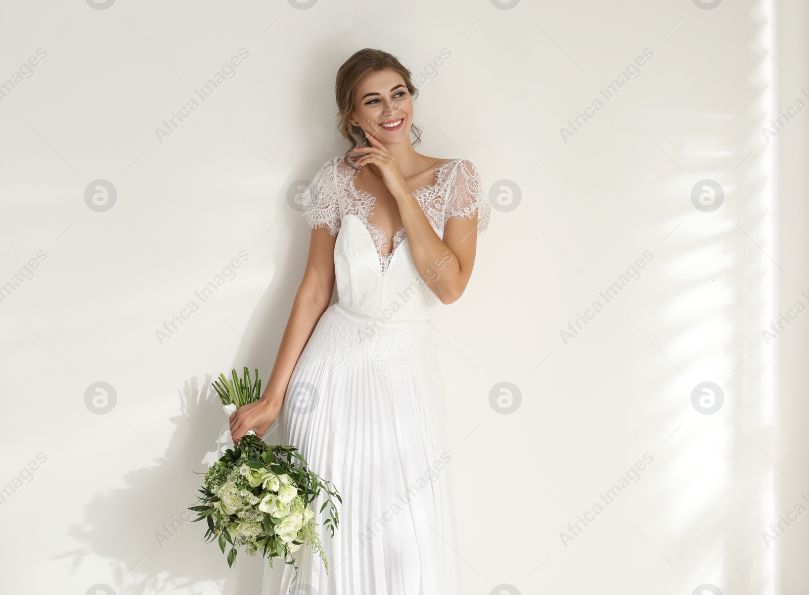 Photo of Young bride wearing wedding dress with beautiful bouquet on light background. Space for text