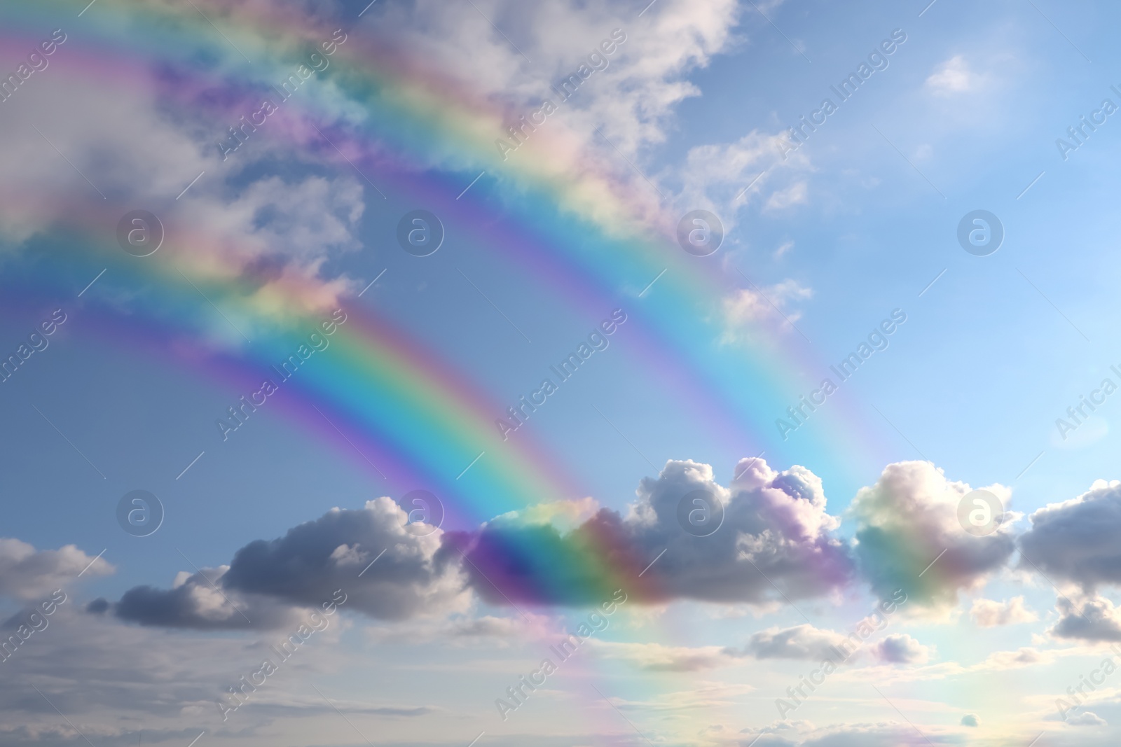 Image of Beautiful view of bright rainbows in blue sky on sunny day