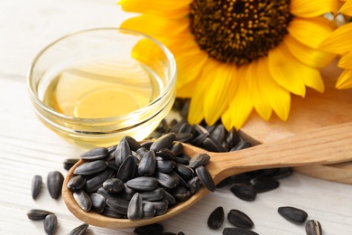 Photo of Sunflower seeds and oil on white wooden table, closeup